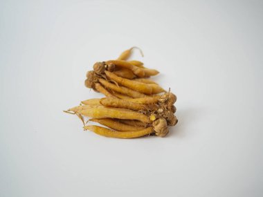 Eğri parmak kökleri yığını toprak tonlarını ve beyaz üzerinde yerel Güneydoğu Asya dokusunu gösteriyor.