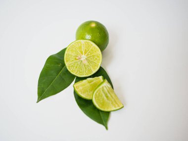 Yeşil kireç ve beyaz zemin üzerindeki dilimlerin minimalist genel görüntüsü ve doğal sağlık ve gıda uygulamaları için yeşil yaprak ile başyazı veya ürün tasarımı