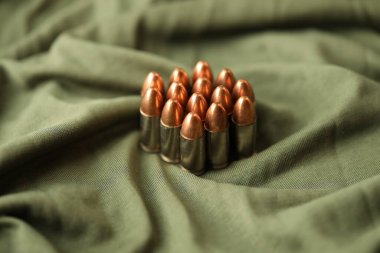 Yeşil kamuflaj üniforması üzerine yığılmış 9mm 'lik tabanca mermileri.