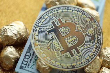 Yüzlerce Amerikan doları üzerinde küçük altın külçeler ve bitcoin kripto para yığını.