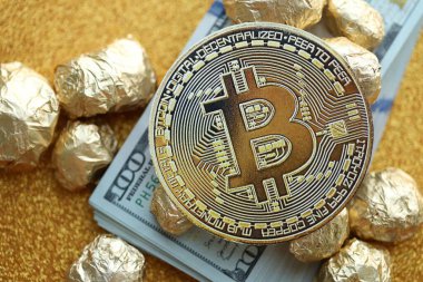 Yüzlerce Amerikan doları üzerinde küçük altın külçeler ve bitcoin kripto para yığını.
