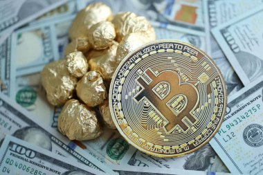 Yüzlerce Amerikan doları üzerinde küçük altın külçeler ve bitcoin kripto para yığını.