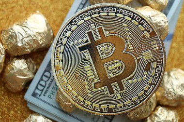 Yüzlerce Amerikan doları üzerinde küçük altın külçeler ve bitcoin kripto para yığını.