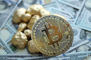 Yüzlerce Amerikan doları üzerinde küçük altın külçeler ve bitcoin kripto para yığını.