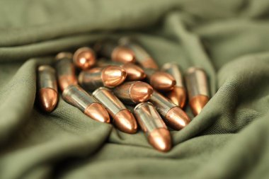 Yeşil kamuflaj üniforması üzerine yığılmış 9mm 'lik tabanca mermileri.