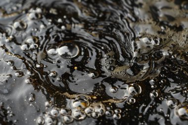 Karanlık gölette köpüklü ham petrolün görüntüsü. Arkaplan kullanımı için doku