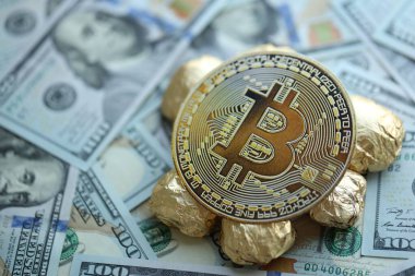 Yüzlerce Amerikan doları üzerinde küçük altın külçeler ve bitcoin kripto para yığını.