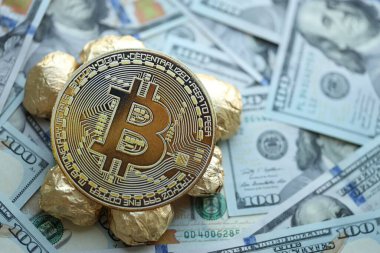 Yüzlerce Amerikan doları üzerinde küçük altın külçeler ve bitcoin kripto para yığını.