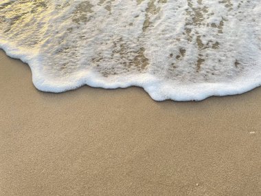 Beyaz köpük dalgaları kumlu sahilde