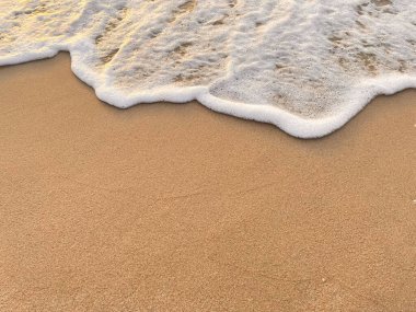 Beyaz köpük dalgaları kumlu sahilde