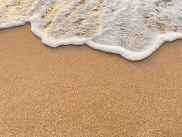 Beyaz köpük dalgaları kumlu sahilde