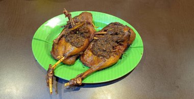 delicious fried duck dish, with crispy skin, well seasoned stuffing make this dish both mouthwatering and flavorful, cuisine meal, presented on vibrant green plate, isolated on brown rough background flavorful fuck, crispy duck, duck dish and cuisine
