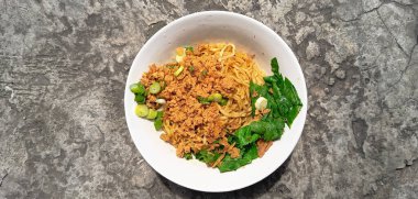 Ortası et suyuyla çevrili büyük köfteli bir kase çorba. Doğranmış yeşil soğanlar köftenin etrafında yüzer, biraz renk katar, basit ve rahatlatıcı, kaba beyaz arka planda izole edilmiş beyaz bir kasede servis edilir.