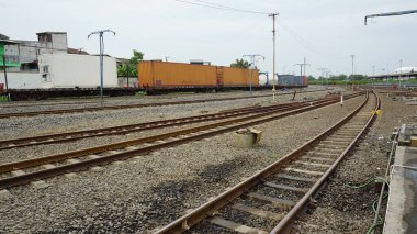 Yük konteynırları ve kesişen raylarla dolu demiryolu tersanesi, birden fazla demiryolu hattı, pist anahtarları, konteynır taşıyan yük trenleri, kargo trenlerinin demiryolu lojistik ve modüller arası nakliye sevkiyatı                               