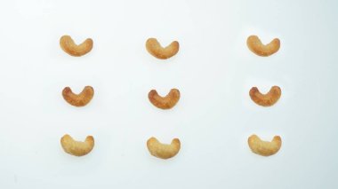 Kızartma seviyesi karşılaştırması için dokuz kaju fıstığından oluşan ızgara, düzgün bir şekilde düzenlenmiş ızgara şablon, sağlıklı atıştırmalıklar, vegan protein ve bitki bazlı ölüm, simetrik olarak konumlandırılmış, renklendirme dokusu, beyaz arka planda izole edilmiş                               