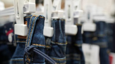 Katlanmış Mavi Kot Sırası Bir Perakende Giyim Mağazasında Beyaz Plastik Askılarda Sallanıyor Denim Giyim ve Giysi Satılık Saha Derinliği ile Satılık