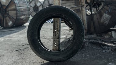 Endüstriyel ortamda Eski Siyah Lastik Metal Kutbuna Yaslanıyor