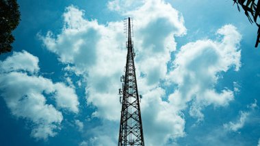 Yüksek telekomünikasyon kulesi 5G parçalı bulutlu mavi gökyüzüne uzanıyor