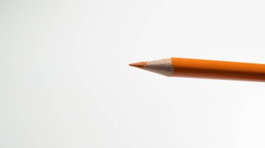 Parlak turuncu bir kalemin minimalist bir görüntüsü, büyümeyi, doğayı ve her yaş için renk sevincini simgeliyor..