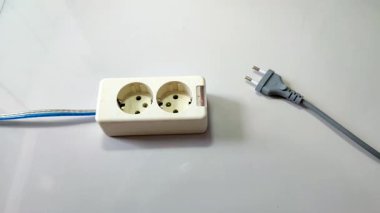 Bir adamın eli elektrik prizine takılıyor. Fişi uzatma kablosuna bağlıyorum.