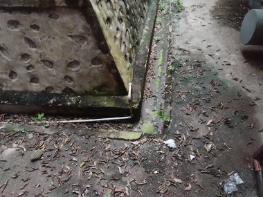 Kaldırımın kenarında kurumuş yapraklarla çevrili bir drenaj çıkışı var.