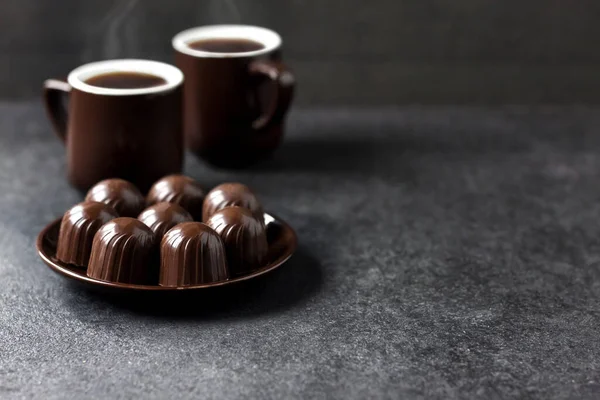Шоколадні Цукерки Тарілці Дві Чашки Гарячої Кави Чорному Тлі Місцем — стокове фото