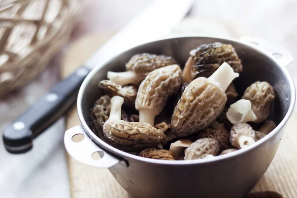 stock image Spring Morel mushrooms in a metal bowl on a wooden cuttung board. Closeup  