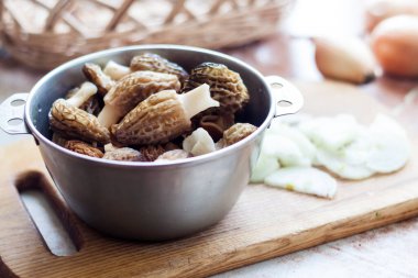 Bahar Morel mantarları ahşap kesme tahtasındaki metal bir kasede. Yakın çekim.  