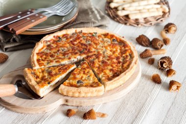 Kiş - ahşap kesim tahtasının üzerinde mantarlı, soğanlı ve mozzarella peynirli turta