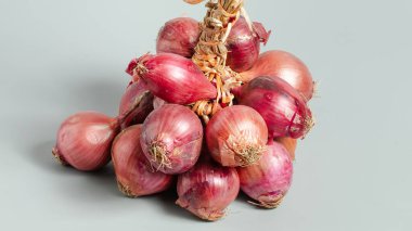 Beyaz arkaplanda bir demet kırmızı soğan.