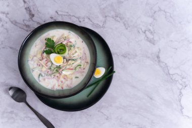 Parlak yeşil bir tabakta taze bir porsiyon okroshka, temiz ve üst düzey bir estetiği vurguluyor.