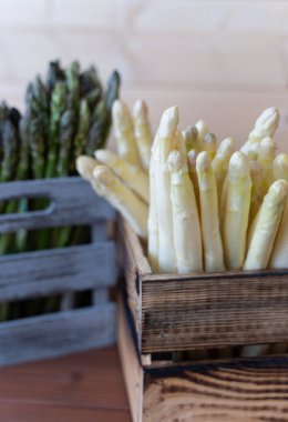 Taze beyaz ve yeşil kuşkonmaz. Hafif ahşap bir sandıkta, bahar yemekleri için mükemmel.