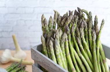 Kırsal gri bir sandıkta Vibrant yeşil kuşkonmaz, doğal rengi ve mevsimsel tazeliği vurguluyor.