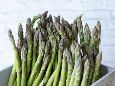 Yıpranmış gri bir sandığa düzgünce dizilmiş yeşil kuşkonmazları kapatın. Pazar ve çiftlik görselleri için ideal.