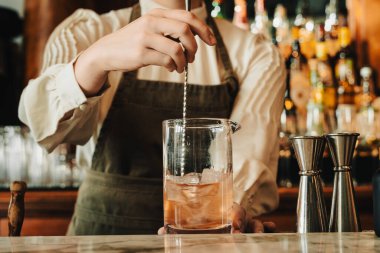 Barmenin kokteyli karıştırırken odaklanmış fotoğrafı. Yanında acı biber ve bar aletleri vardı.