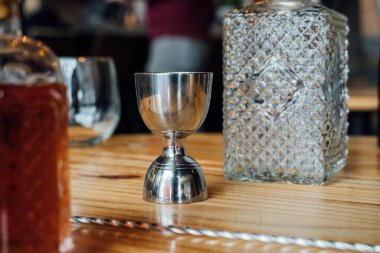 Cilalanmış kokteyl zımbırtısı ve kristal cam sürahi lüks bir barda sergileniyor. İşlenmiş işçiliği ve zarif miksoloji sanatını sembolize eder.