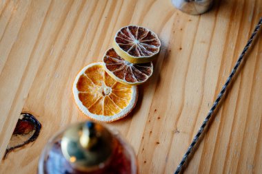 Limon ve portakal da dahil olmak üzere çeşitli kurutulmuş narenciye dilimleri kırsal bir ahşap bar yüzeyinde sergileniyor. Lüks kokteyl sunumları, miksoloji düzenlemeleri ve birinci sınıf garnitür tasarımları için ideal..