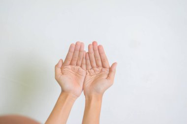 Genç Müslüman kadının elleri beyaz arka planda yalnız dua ediyor..