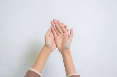 Genç Müslüman kadının elleri beyaz arka planda yalnız dua ediyor..