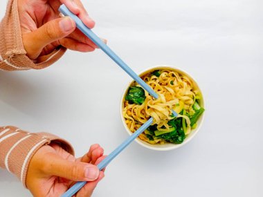 Beyaz arka planda tavuklu erişte. Elin yemek için çubuklu erişte alıyor. Fast food. Modern yemek..