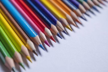 Yaratıcılık, öğrenme ve sanatsal ifadeleri okul ve eğitim temaları için mükemmel bir şekilde temsil eden, beyaz bir yüzeyde köşegen şeklinde keskinleştirilmiş renkli kalemler.