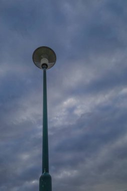 Bulutlu Gökyüzüne Karşı Sokak Lambası. Uzun bir sokak lambası bulutlu bir gökyüzünün arka planında duruyor..