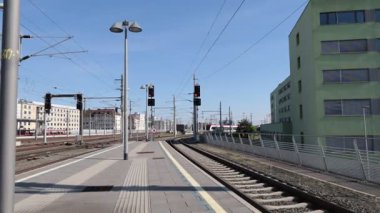 Şehir Tren İstasyonu 'na modern tren geliyor. Pürüzsüz, modern bir tren, açık mavi gökyüzünün altında bir tren istasyonuna yaklaşıyor..
