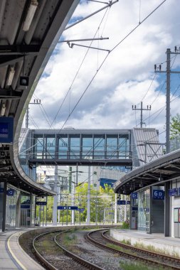Tepedeki yaya köprüsü olan modern tren istasyonu. Kıvrımlı rayların ve yaya köprüsünün bulunduğu çağdaş bir tren istasyonu..