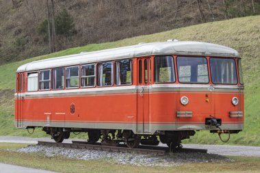 Vintage Orange Railcar ekranda. Bir pistte açık havada sergilenen klasik turuncu bir tren vagonu.