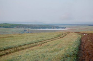 Sabah Gölü 'nün üzerindeki sis. Güneş doğarken yüksek kaliteli bir fotoğraf, durgun gölün üzerinde asılı duran yumuşak bir sis, dingin ve gizemli bir atmosfer yaratır. Sakin bir sabah, zamanın sisli havada durduğu suyu kucaklıyor..