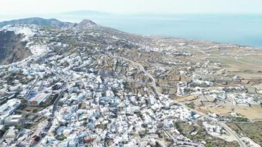 Drone, Santorini 'nin başkenti Fira üzerinde ateş açtı. Şehir manzarası, volkanik kayalıklar, deniz ve yakındaki adalar. Yüksek kalite 4k görüntü