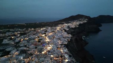 Oia, Santorini 'deki Caldera Cliffs üzerinde akşam uçuşu. Yumuşak Işıklar ve Uzak Ufuk. Yüksek kalite 4k görüntü