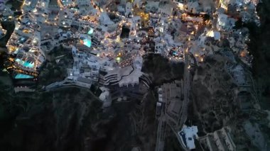 Oia, Santorini, Beyaz Yıkanmış Kubbeler ve Altın Sokak Işıkları üzerindeki hava alacakaranlığı. Yüksek kalite 4k görüntü