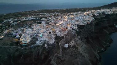 Oia, Santorini 'nin Akşam Manzarası - Beyaz Saray ve Parlayan Caddelerin Havadan Çekimi. Yüksek kalite 4k görüntü